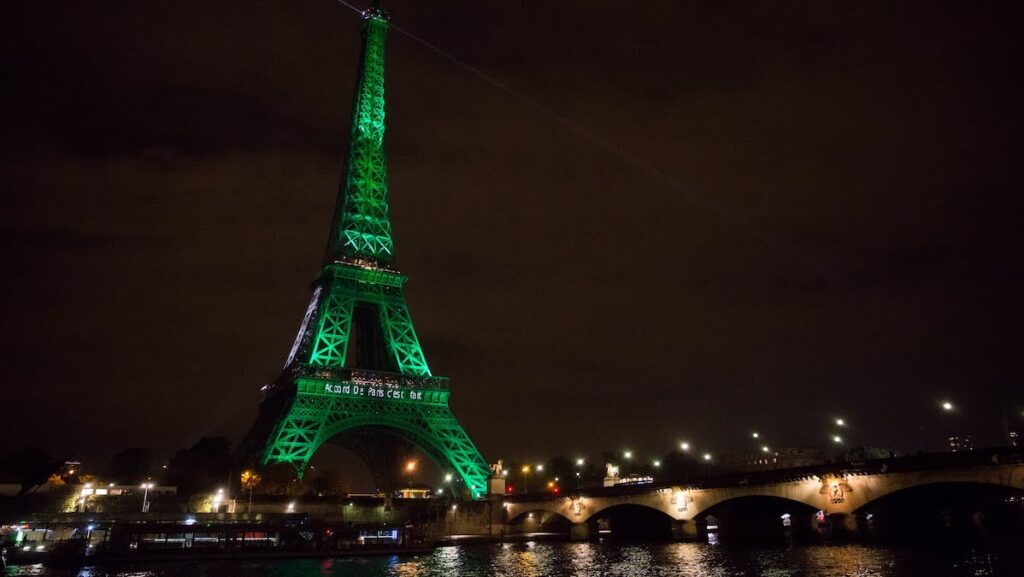 The Eiffel Tower at night, lit up by green lights. Text projected on the Eiffel Tower reads “Accord De Paris c’est fait,” meaning “Paris Agreement is done.”
