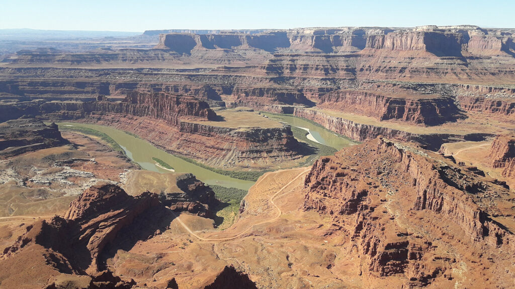 A river curves back and forth through a series of layered red plateaus.