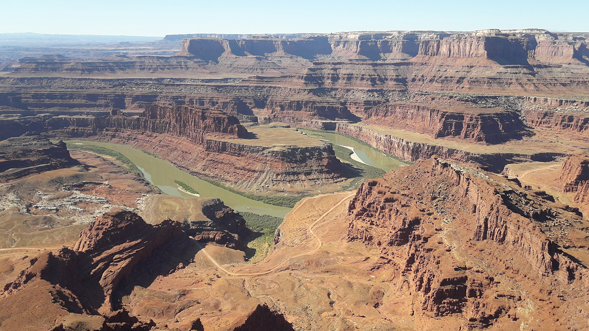 A river curves back and forth through a series of layered red plateaus.