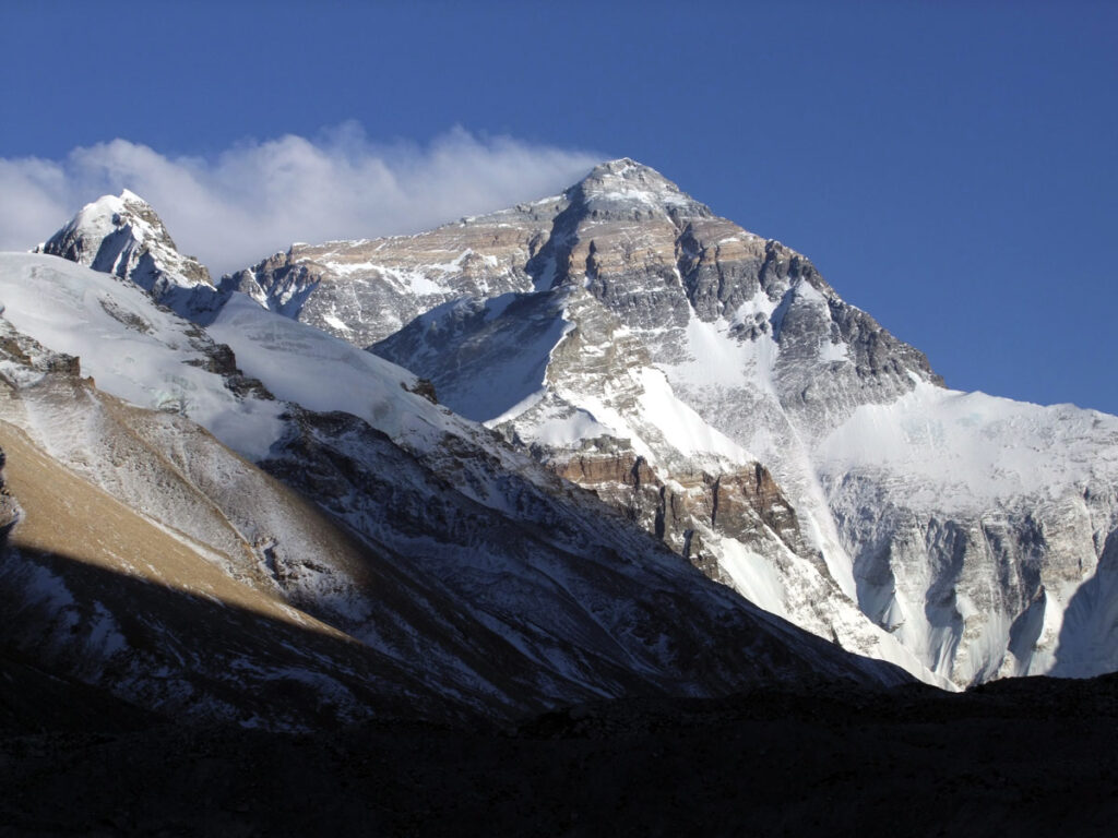 Rocky mountain with patches of snow illuminated by sunlight.