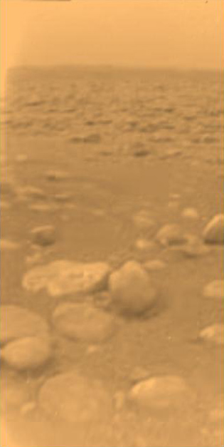 View from the surface of Titan of an orange sandy plain with boulders