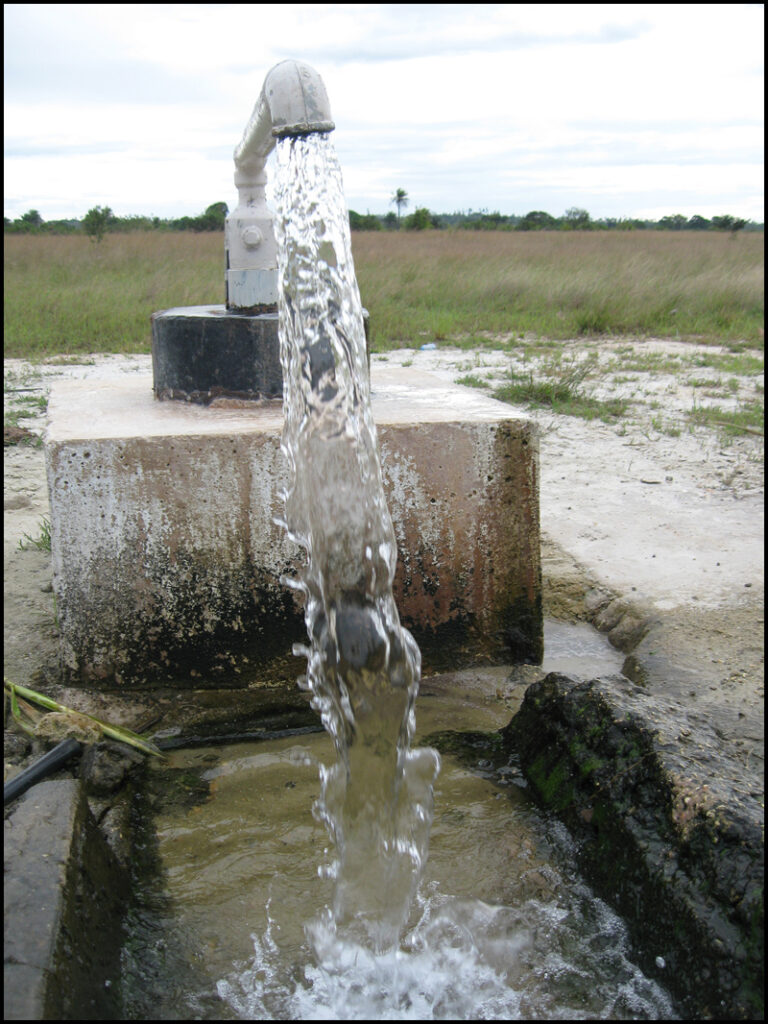 Close-up view of water pouring from an outdoor tap into a concrete receptacle