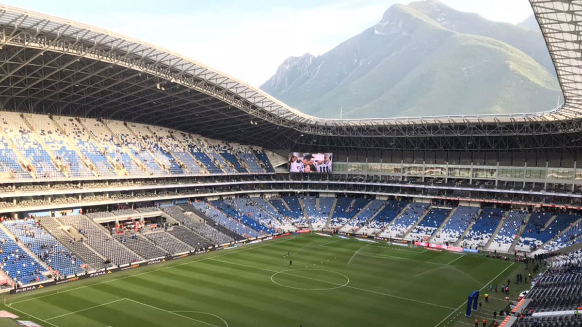 View of a soccer stadium from the upper levels. A green mountain is visible in the background.