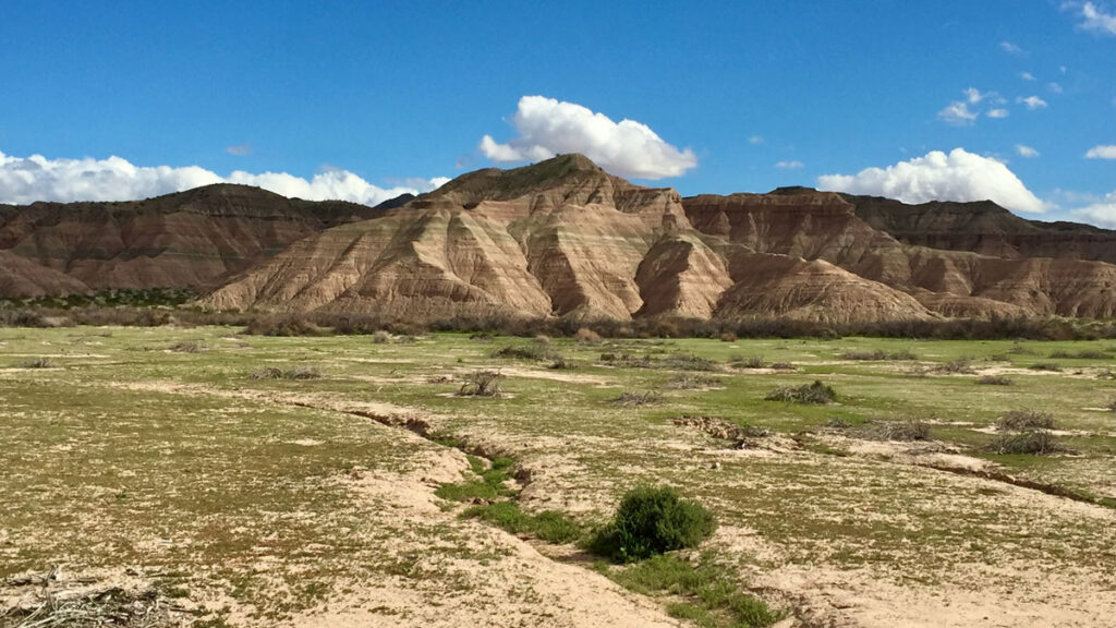 A rock formation with many layers sits beneath a blue sky.