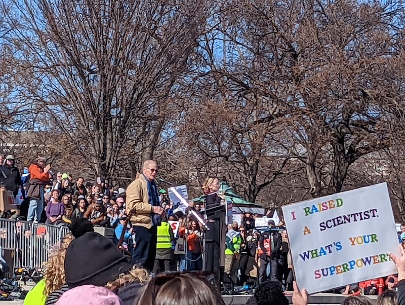A person stands on a small stage in front of a crowd.