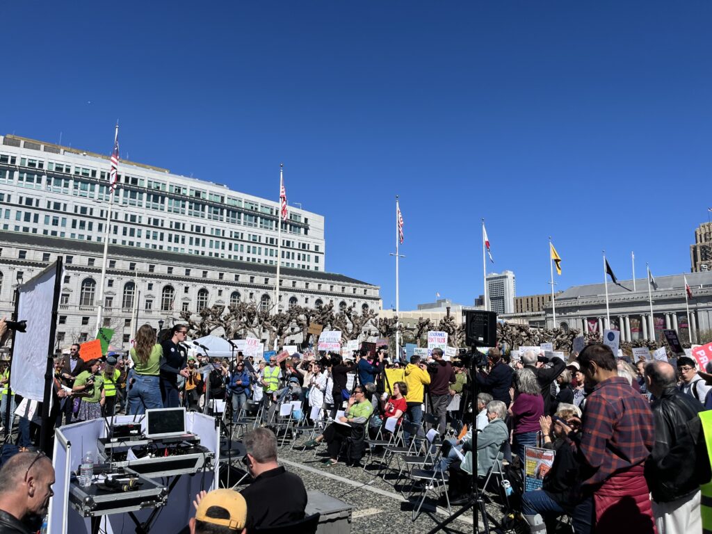A rally crowd gathers in front of a stage.
