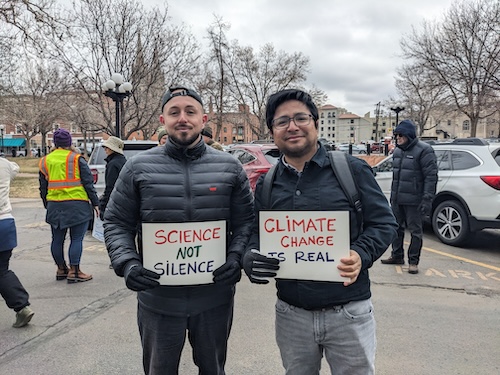 Scientists hold protest signs saying "Science Not Silence" and "Climate Change Is Real"