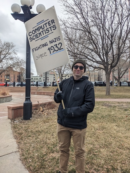 A protester carries a sign: Computer Scientists, fighting Nazis since 1932