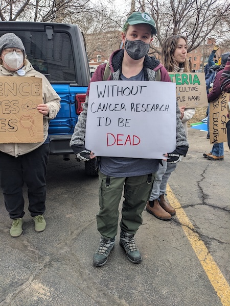 Protest sign: Without cancer research, I'd be dead