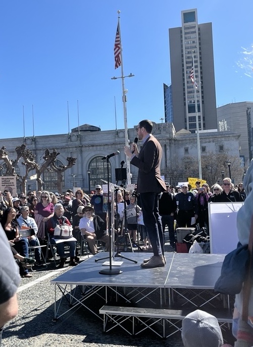 A person speaks into a microphone on front of a crowd