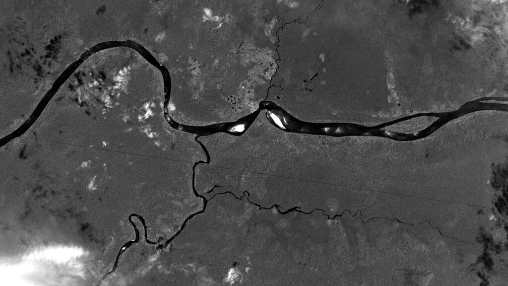 A black-and-white satellite image shows a small river branching off from a larger one.