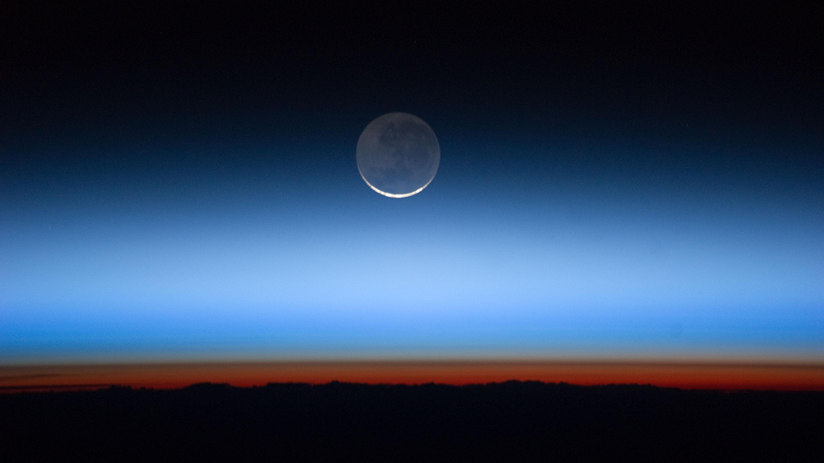 Photo of Earth's atmospheric layers with the moon in the background.