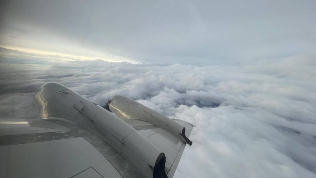 The wing of an airplane above dense white clouds on a stormy day