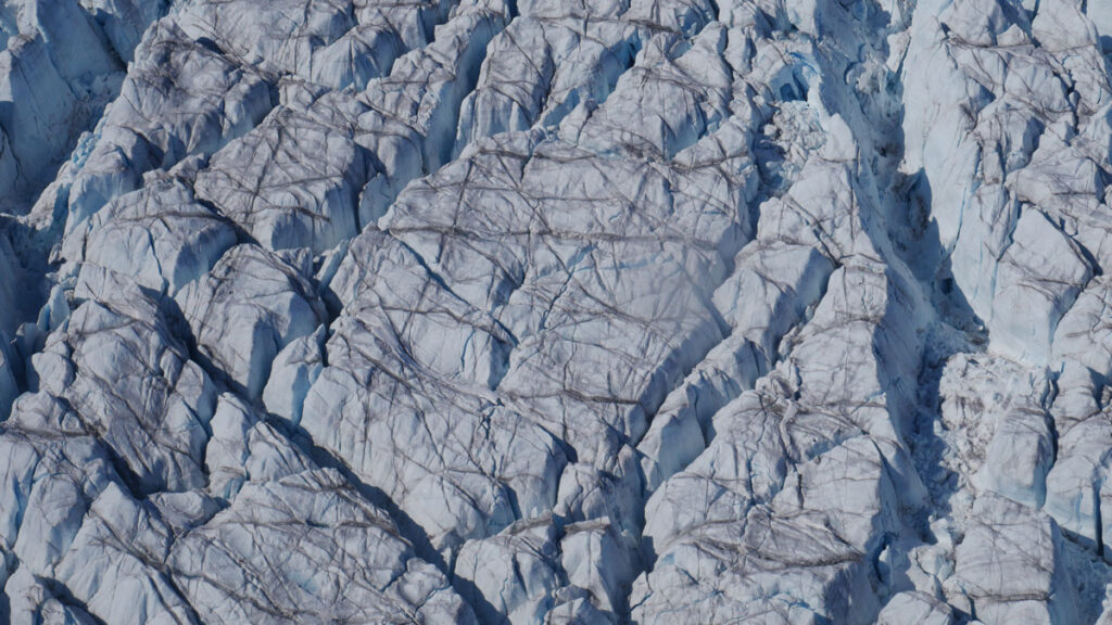 An aerial view of crevasses crisscrossing the surface of a glacier