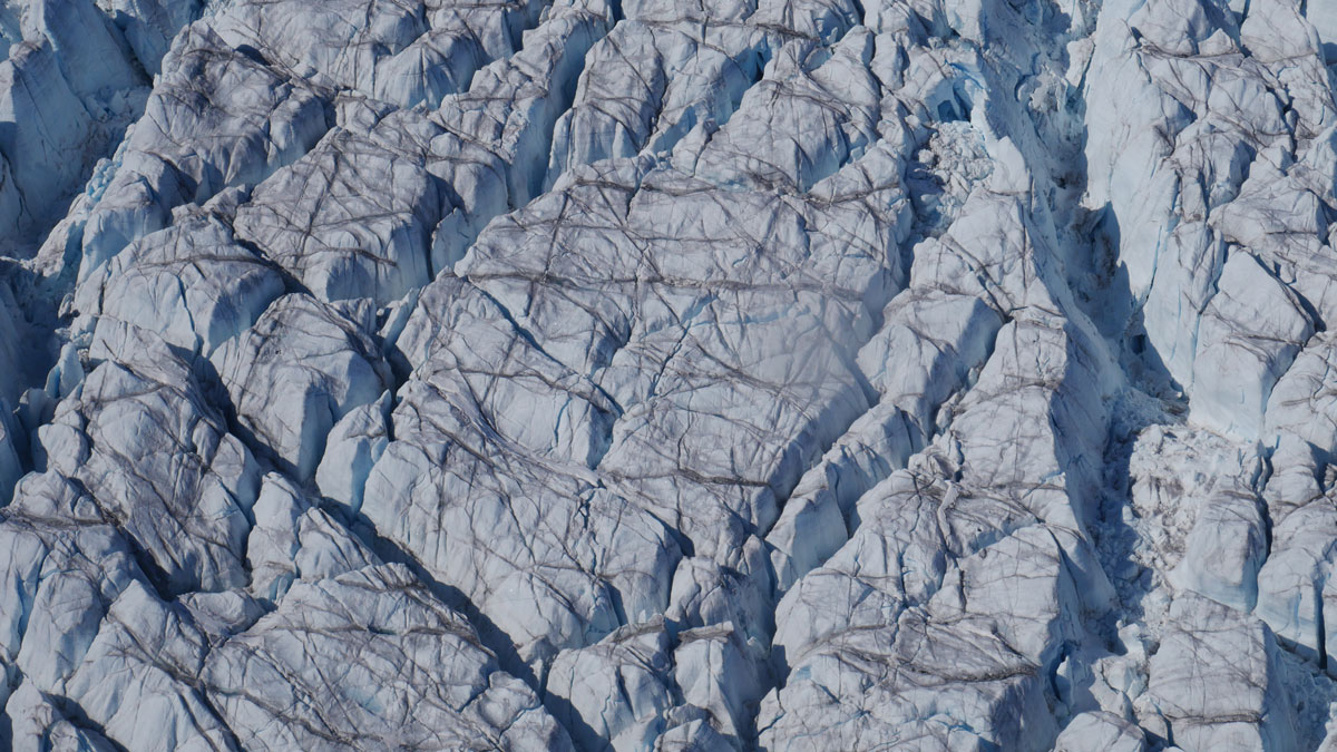 An aerial view of crevasses crisscrossing the surface of a glacier