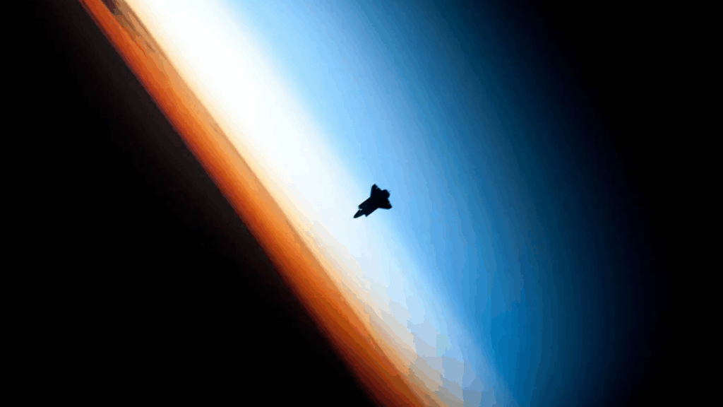 Photo of a space shuttle in front of Earth's atmosphere.