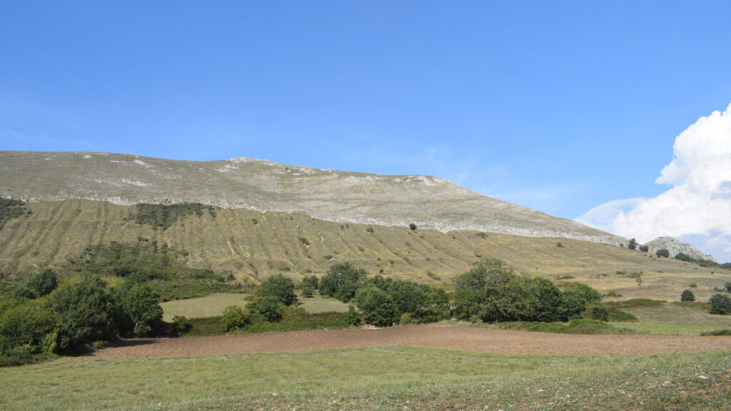 A green hill sits beneath a blue sky.