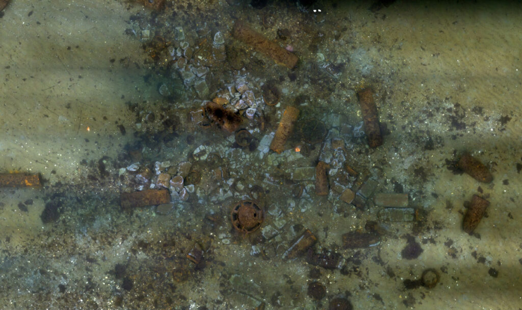View looking down on scattered rusting metal shapes on the seafloor