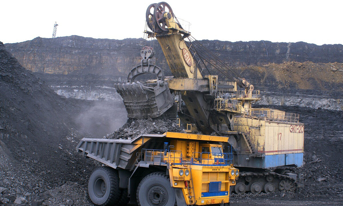 A large vehicle dumps a load of coal into another large vehicle.