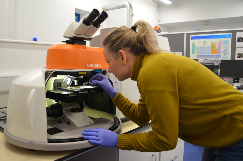 Victoria Rossi places a fossil sample underneath a microscope.