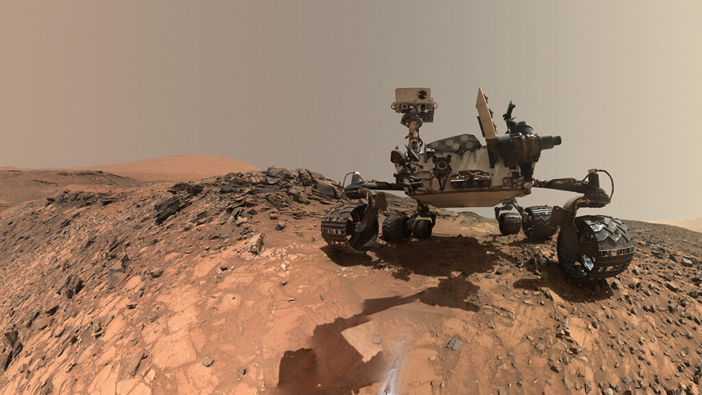 The Curiosity rover perched on top of a hill on the surface of Mars