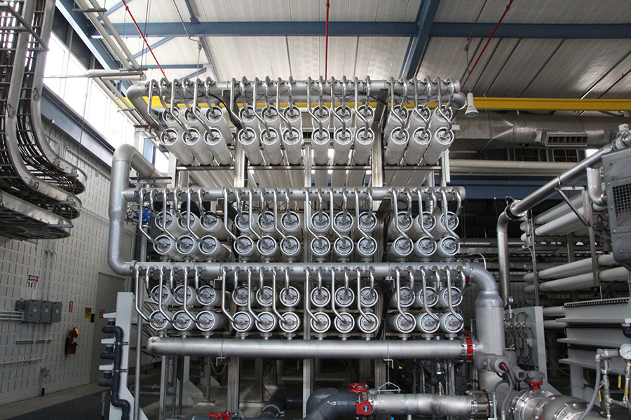 A large, complicated network of metal pipes stretches toward the ceiling of a warehouse.