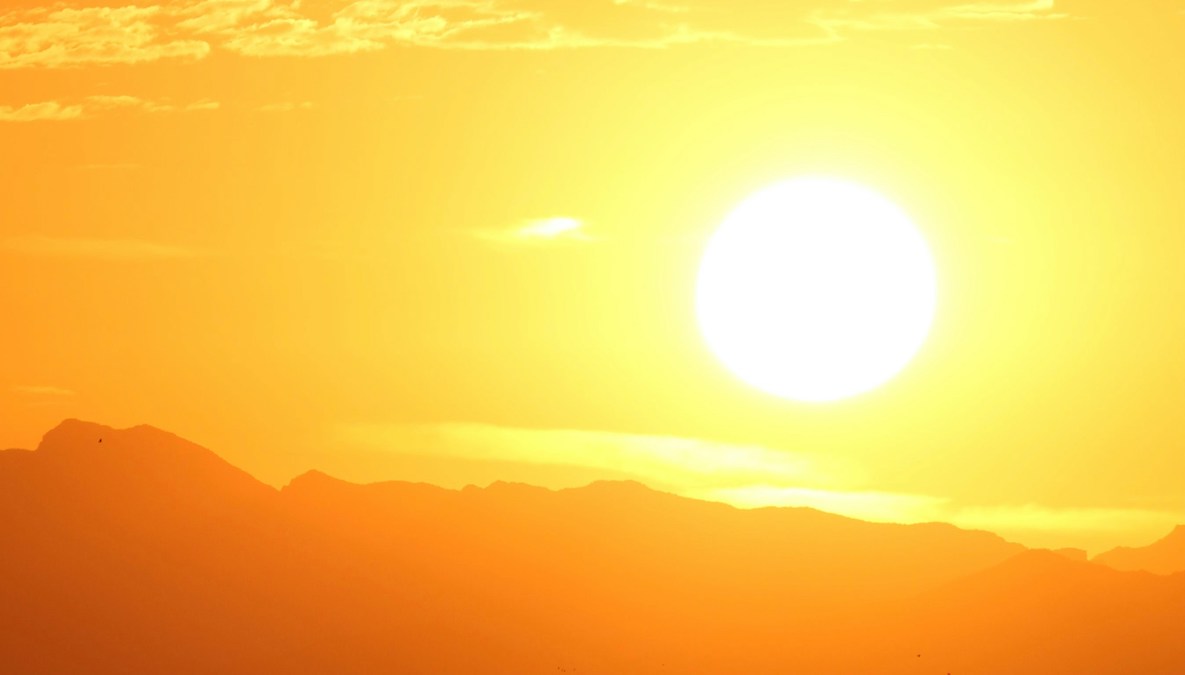 A bright Sun at sunset over a rocky landscape.