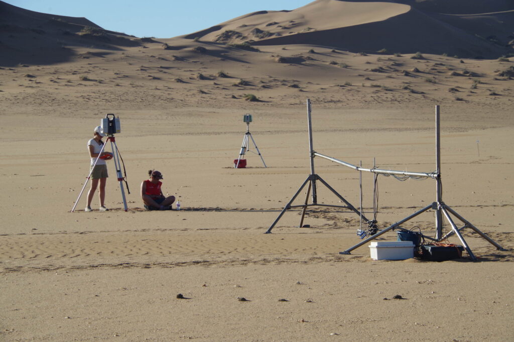 Scientific equipment installed near a small patch of wavy sand in a desert.