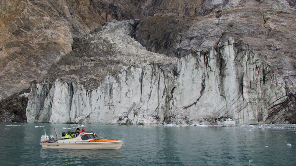 A small vessel sails past a glacier.