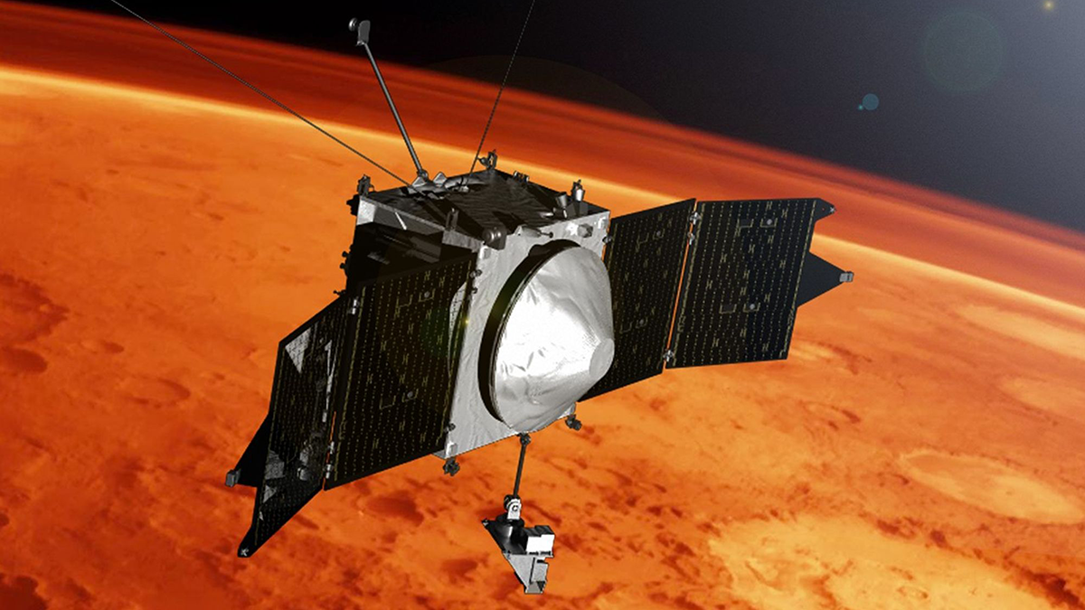A silver-colored spacecraft orbits above a red-colored planet with craters visible on its surface.