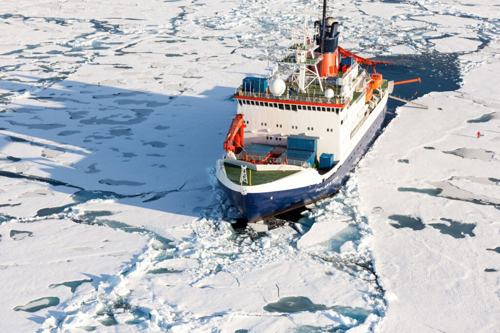Aerial view of the R/V Polarstern sailing through sea ice in the Arctic Ocean.