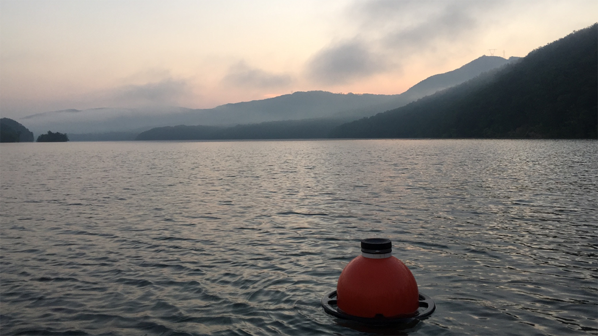 Photo of a buoy in a lake with mountains in the background.