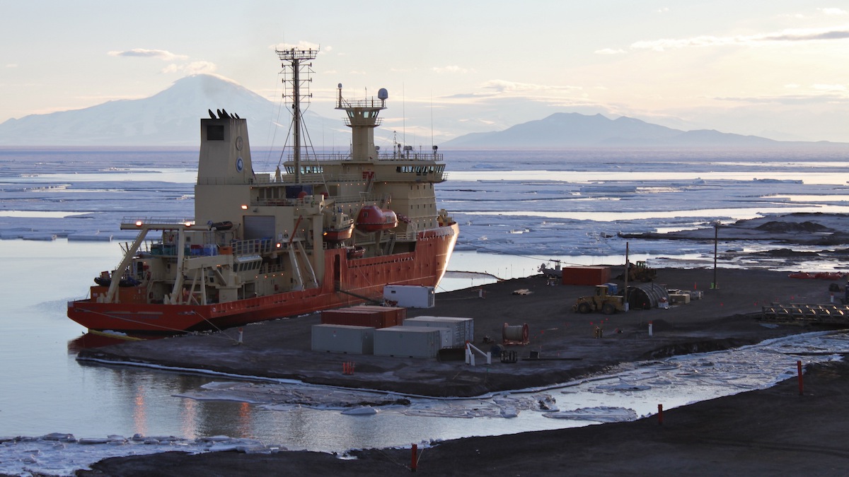 A large icebreaking ship docked in a shipyard among sea ice.