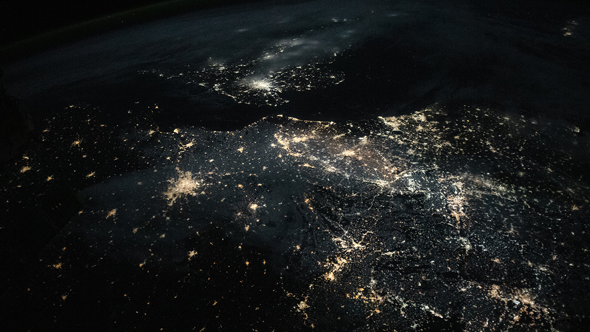 A satellite image of northwestern Europe at night shows several urban centers that appear as bright clusters of light.