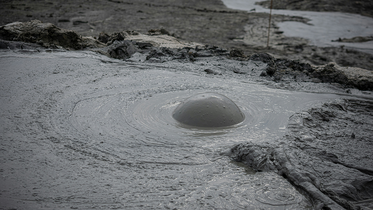 A pool of brown mud with a large bubble near the center of the image