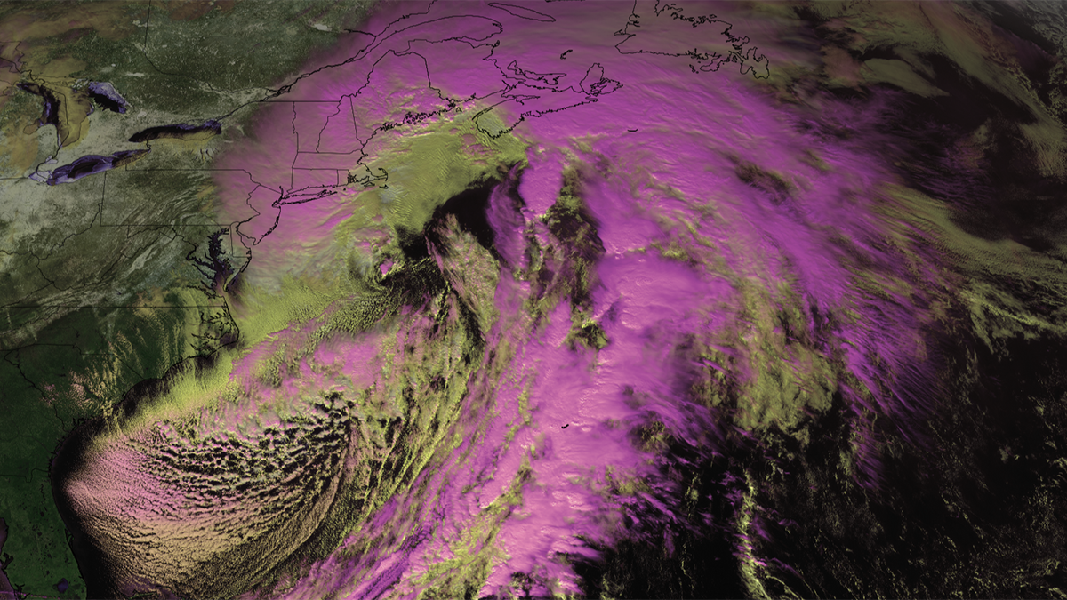 A satellite image shows the Atlantic Ocean and the eastern coast of the United States. The area is covered with clouds that have been colored yellow and pink to indicate their altitude.