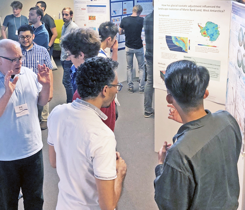 People chat with one another other while standing amid posters displaying their research.