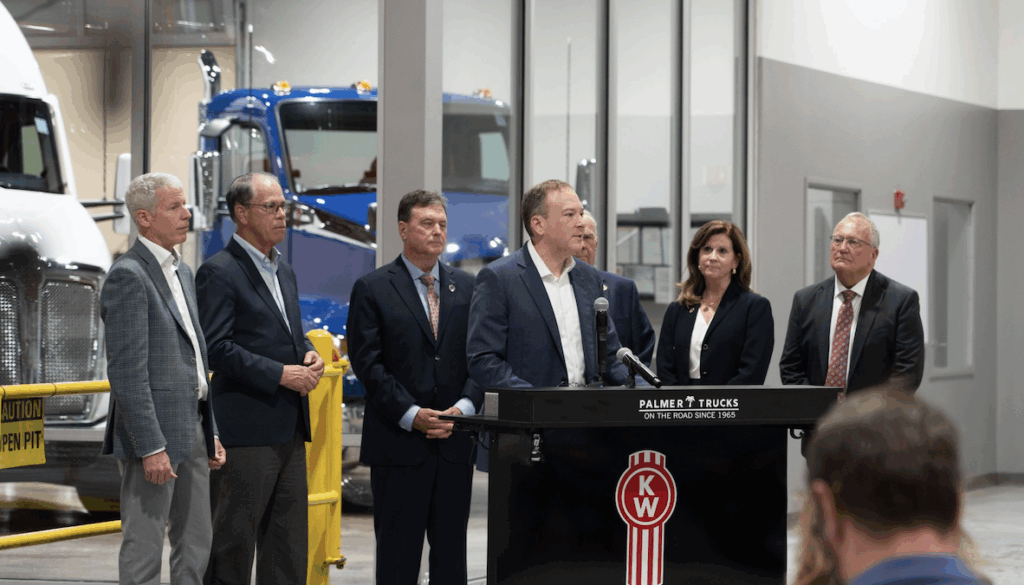 EPA Administrator Lee Zeldin speaks at a podium in an auto dealership, with other EPA staff and stakeholders standing behind him.