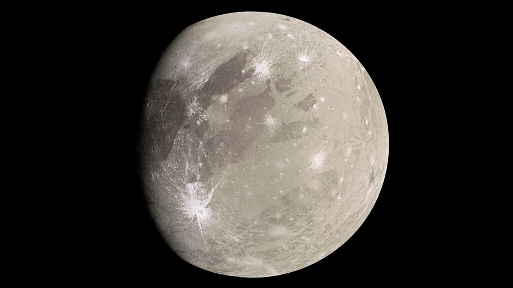 A light tan world marked with bright white craters from meteor impacts