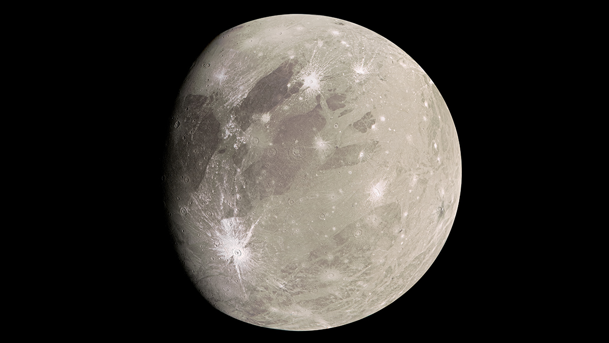 A light tan world marked with bright white craters from meteor impacts