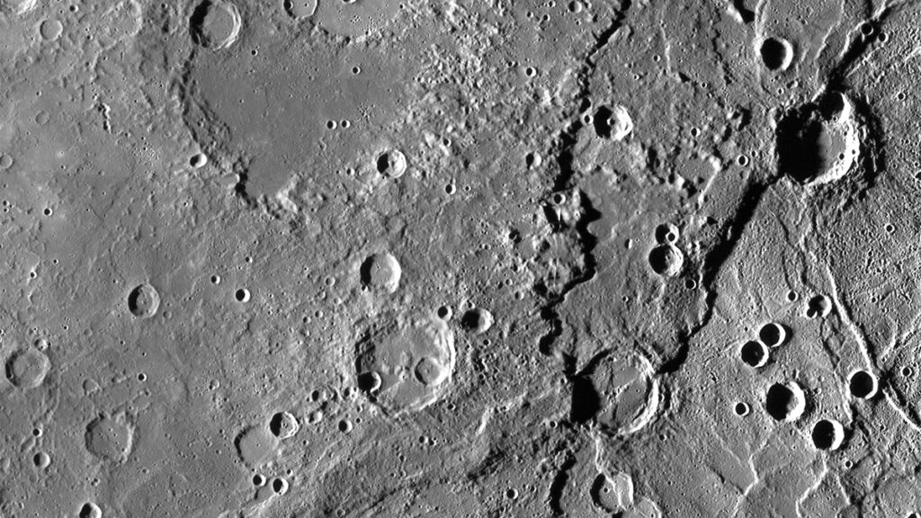 A photo of a gray surface pockmarked with craters, as well as a line representing a fault.