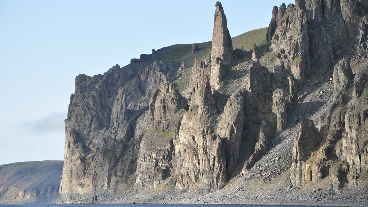 Gray-brown cliffs with spires next to a body of water