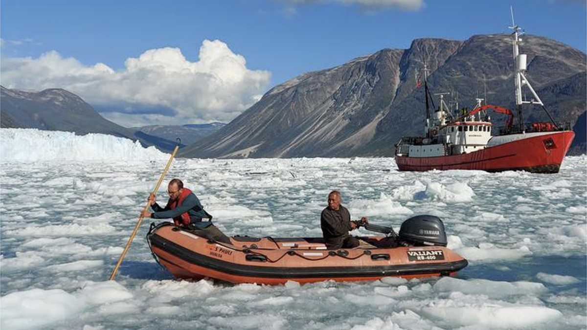 Two men in a Zodiac navigate icy waters.