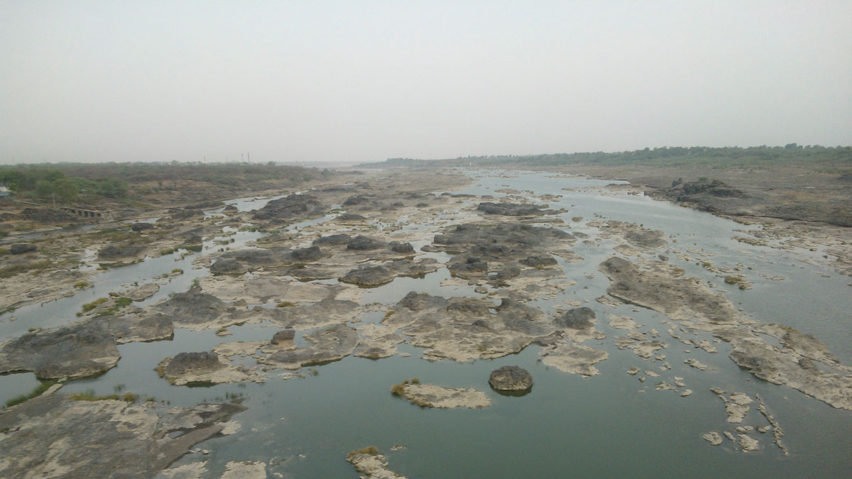 A shallow green-blue river with large brown-gray rocks.