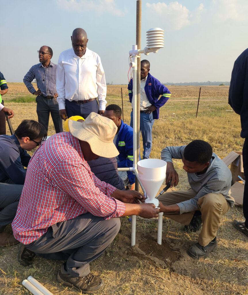 A team of people installs a rain gauge mounted on plastic posts.