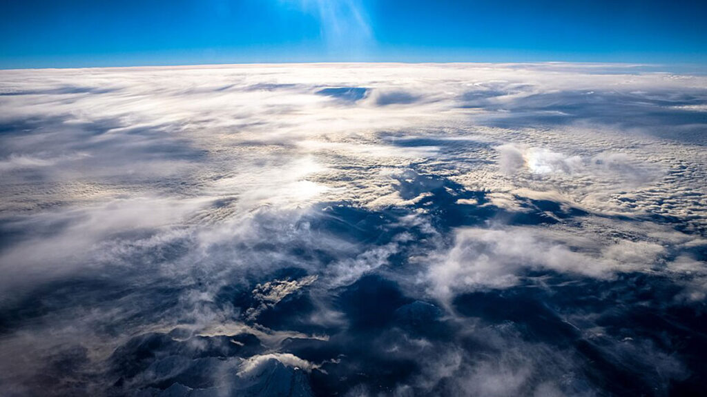 Aerial photo of clouds dusting a mountainous landscape.