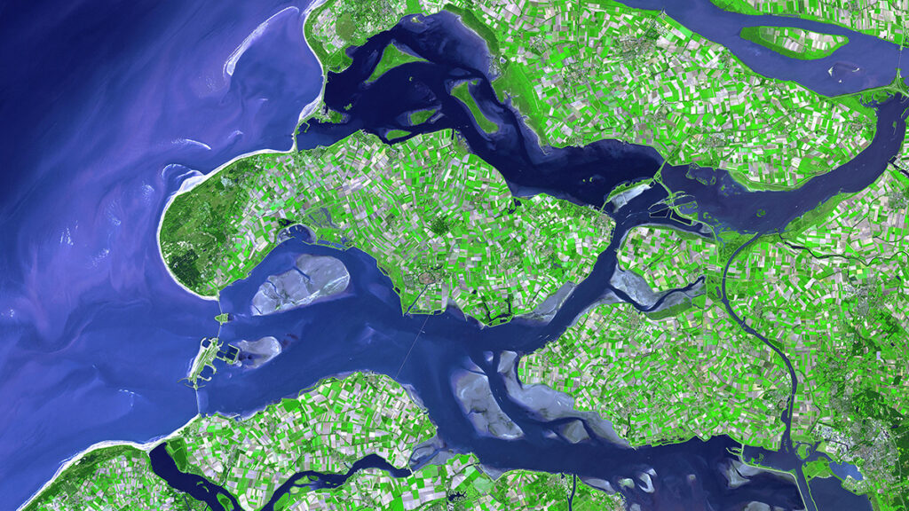A satellite view of the southwestern coastline of the Netherlands shows a crisscross of rivers, estuaries, and canals.