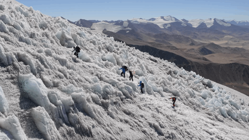 Five expedition team members climb an icy surface.