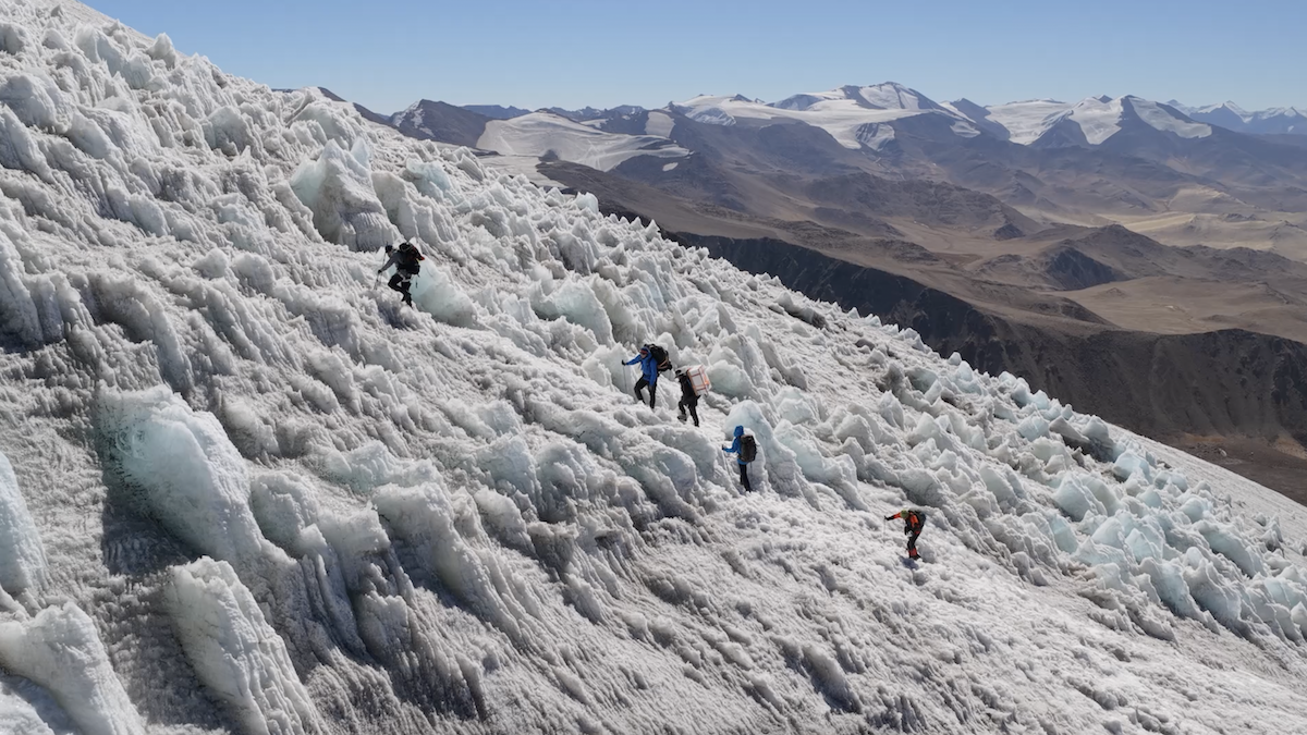 Five expedition team members climb an icy surface.