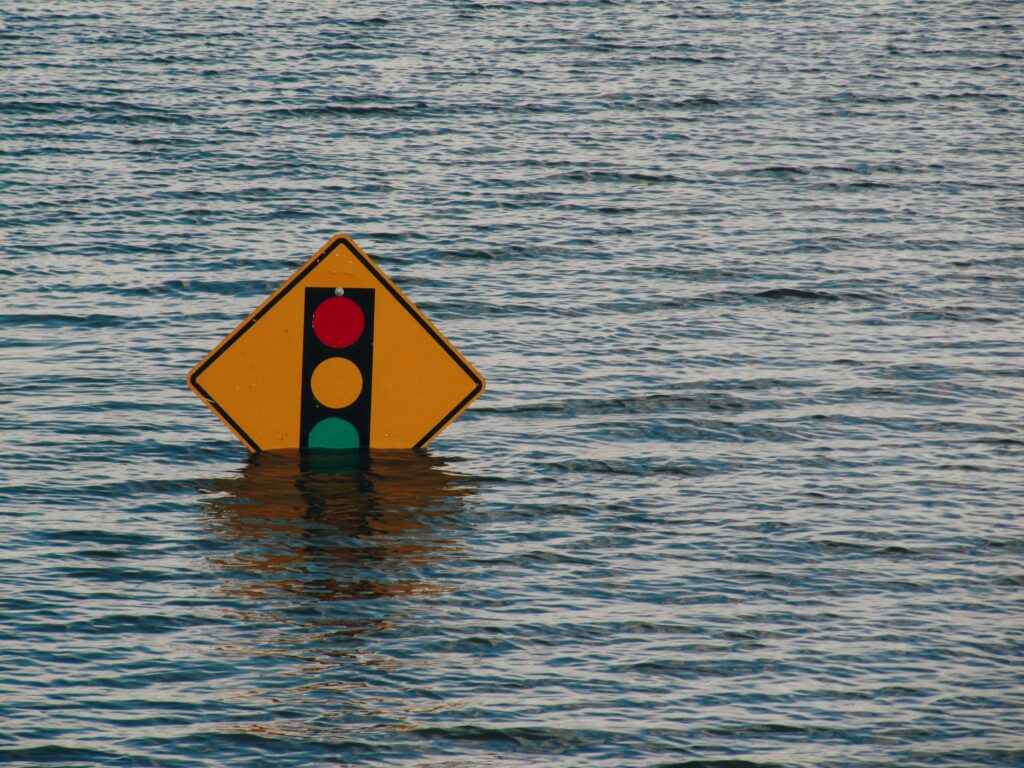 A street sign halfway submerged in floodwaters.